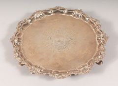 A GEORGE II SILVER PIECRUST SALVER with cast border and crest on three hoof feet. 11ins diameter.