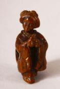 A JAPANESE MEIJI PERIOD CARVED WOOD NETSUKE OF A LADY - The lady stood with her hands together,
