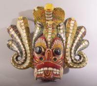 A LARGE SRI LANKAN CARVED AND PAINTED WOODEN MASK, 33cm x 45cm.