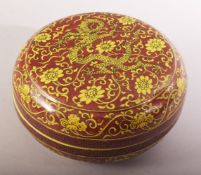 A CHINESE RED GROUND PORCELAIN CIRCULAR BOX AND COVER, painted with yellow dragons and flower