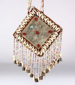 AN ISLAMIC CEREMONIAL NECKLACE, the plaque with cowrie shell border, 15.5cm square.
