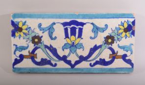 AN INDIAN MULTAN GLAZED TERRACOTTA TILE PANEL, with foliate motif, 30.5cm long.