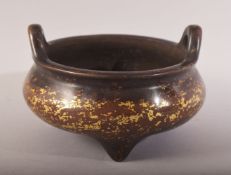 A CHINESE GILT SPLASH BRONZE TWIN HANDLE CENSER - on three feet with twin handles - the base with