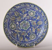 A PALESTINIAN GLAZED POTTERY PLATE, painted with flower head motifs, 22.5cm diameter.