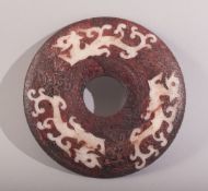 A SMALL CHINESE RED STAINED HARDSTONE BI DISK, with three stylised chilong, 10.5cm diameter.