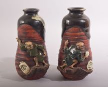 AN UNUSUAL PAIR OF SMALL JAPANESE FIGURAL POTTERY VASES, the rim and neck glazed, with two moulded