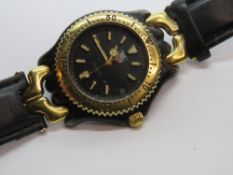 A Tag Heuer wristwatch having gold plated bezel with black dial, date aperture, black leather strap.