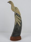 A horn carved into a figure of a bird and mounted upon wooden base, standing 29.