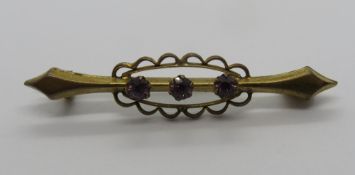 A yellow metal brooch set with three round cut purple stones, 4cm, 1.5g.