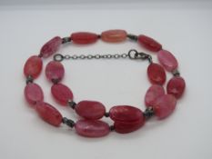 A hot pink hard stone necklace having 925 silver clasp.
