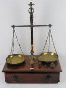 An impressive set of brass balance scales set on mahogany base with drawer under,
