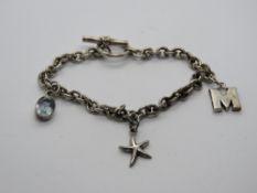 A silver charm bracelet having 925 aquamarine charm and star fish charms upon,