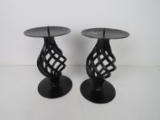 A pair of black painted metal candle sta
