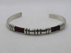 A sterling silver bangle having snake sk