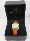 A Klaus-Kobec Charisma wristwatch on tan leather strap having cream dial with date aperture. In box.