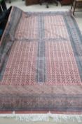 A large four panel red ground rug having geometric design to border, 294 x 190cm, slightly a/f.
