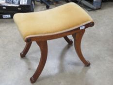 An Edwardian mahogany calimnos stool having four outswept legs and decorative carved roundels
