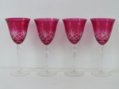 Four cranberry glass wine glasses, 23cm high.