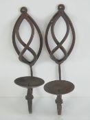 A pair of wrought iron wall mounted candle sconces, each measuring 30cm in length.