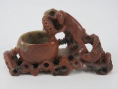 A Chinese soap stone brush pot, carved and pierced and bearing monkey figuring upon, 14cm wide.