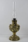 An embossed brass oil lamp with glass chimney, all standing 53cm high.
