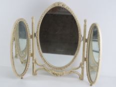 An oval tryptic dressing table mirror, cream and gilt floral frame, all standing 54cm high.