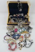 A quantity of assorted costume jewellery contained within purple velvet jewellery box.