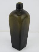 A vintage square-shaped green glass gin bottle having triangular mark to base and applied A.H.