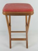 A vintage 1960's beech folding stool with red leatherette seat, 50cm high.
