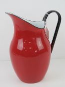 A red and black enamelled tin water jug standing 26cm high.