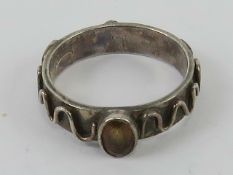 A HM silver ring in Arts and Crafts style having oval orange coloured stone to centre and raised