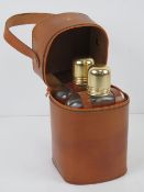 A pair of glass after shave bottles in hide sleeves complete with carry case.