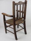 A vintage oak child's straw seated open armchair.