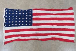 A US flag having 48 stars upon, sewn fabric stripes, printed stars and measuring 145 x 80cm.