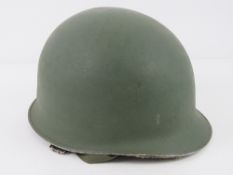 A WWII US helmet having liner and chin strap.