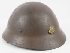 A WWII Japanese Police helmet with liner, chin strap and bearing Japanese writing within.