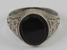 A mens silver and onyx signet ring having engraved decoration to shoulders,
