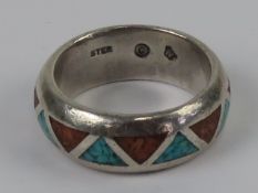 A Native American sterling silver band ring with inlaid triangles of turquoise and coral,