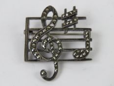 A silver and marcasite 'sheet music' brooch in the form of a treble clef, sharp symbol and F note,