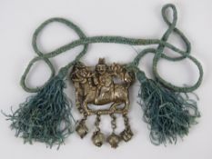 A Chinese white metal two sided pendant in the form of a Qilin (Kirin or Girin) with smiling rider,