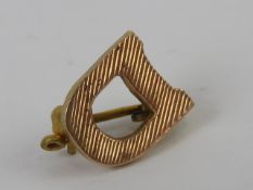 A 10ct gold brooch in the form of a 'D',