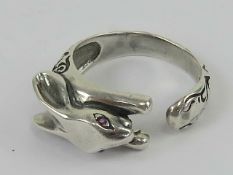 A silver ring in the form of a hare with red stone eyes having engraved decoration throughout,