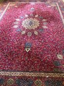 A large an impressive woolen and silk red ground floral carpet having geometric decoration upon,