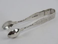 An HM silver pair of sugar tongs having floral engraving upon and hallmarked Birmingham 1892 with