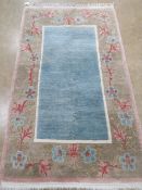 A good woollen and silk floral design rug with central blue panel measuring 166 x 101cm.