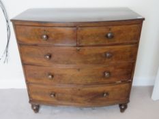 A mahogany barrel fronted chest of two short over three long drawers, raised over turned bun feet,