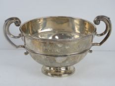 An HM silver pedestal bowl having twin handles and raised over single foot,