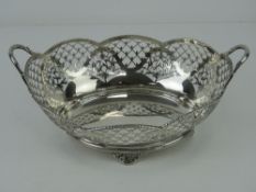 A HM silver twin handled fruit bowl having pierced decoration and raised over four floral feet,