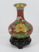 A single early 20th century cloisonné floral vase raised over Oriental hardwood stand, 16cm high.