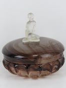 An Art Deco glass powder bowl having seated female to lid, 15cm wide.